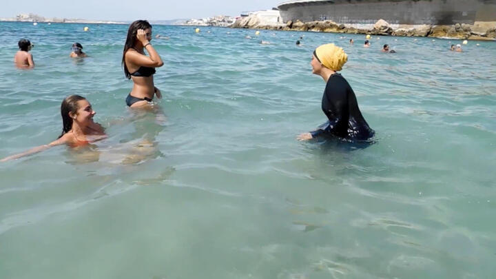 In this image taken from video, Nesrine Kenza who says she is happy to be free to wear a burkini, and two unidentified friends wade into the sea, in Marseille, France, Monday Aug. 29, 2016.